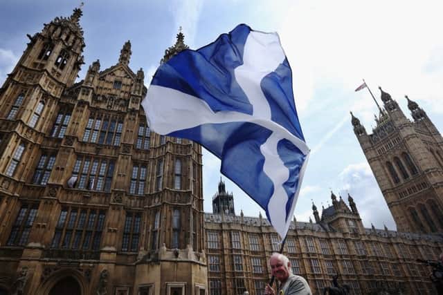 A supporter waves a Scottish flag as the 56 SNP MPs gather for a photocall. Picture: Getty