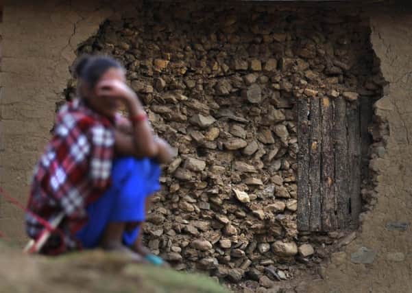 A Nepalese woman sits outside her house damaged in last months earthquake on the outskirts of Lalitpur, Nepal. Picture: AP