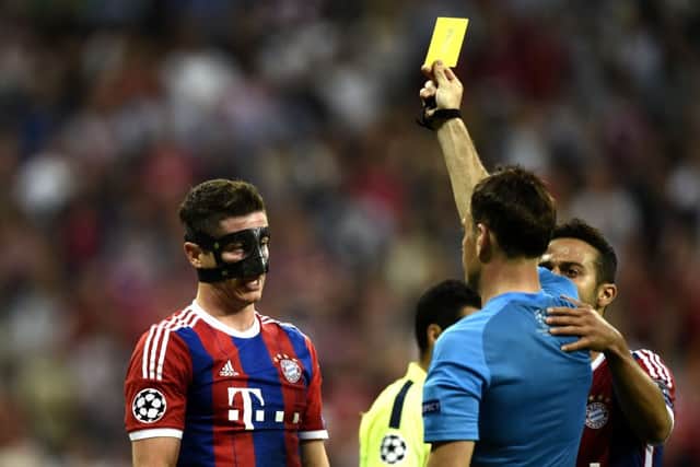 Bayern Munich forward Robert Lewandowski (L) receives a yellow card from British referee Mark Clattenburg. Picture: Getty