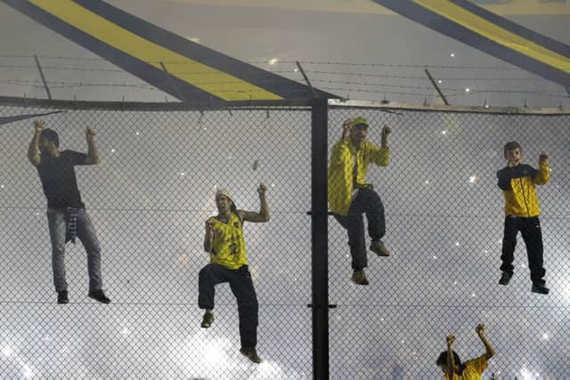 Boca Juniors fans climb a fence during the Copa Libertadores match against River Plate. Picture: AP