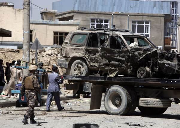 Afghan security forces remove a destroyed vehicle after the suicide bombing near Kabuls international airport. Picture: Rahmat Gul/AP