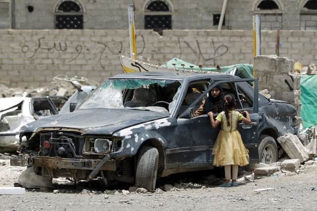 A Yemeni woman inspects a damaged car in a residential area that was destroyed by Saudi-led air strike last month, in Sanaa. Picture: Getty