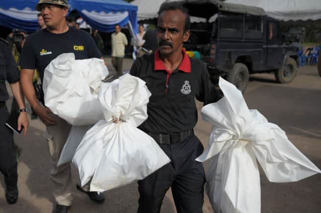 A Malaysian policeman carries human skeletal remains inside plastic bags exhumed from the graves. Picture: Getty