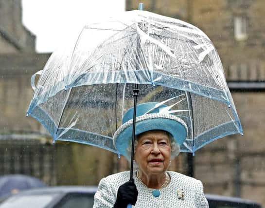 Long may she rain? The Queen shelters during a visit to Lancaster yesterday. Picture: AFP/Getty