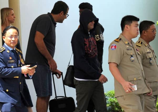 A refugee held in Australian custody on the island of Nauru is escorted by Cambodian police on arrival at Phnom Penh airport. Picture: Getty