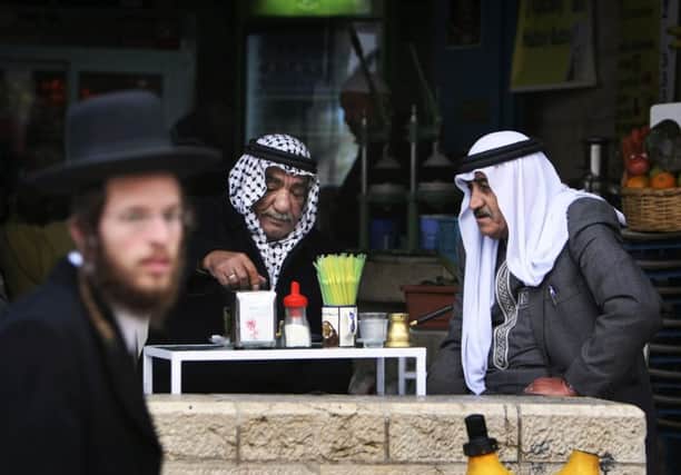 An ultra-orthodox Jewish man passes Palestinians sitting in a coffee shop in Jerusalems Old City. Picture: AP