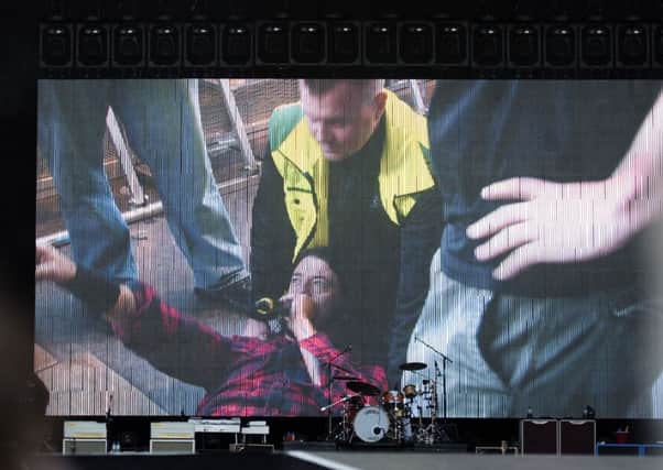 A screen shows Foo Fighters singer Dave Grohl lying down as his leg is attended to. Picture: Getty