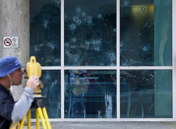 An FBI man by the bullet-riddled window of Dallas police headquarters. Picture: AP