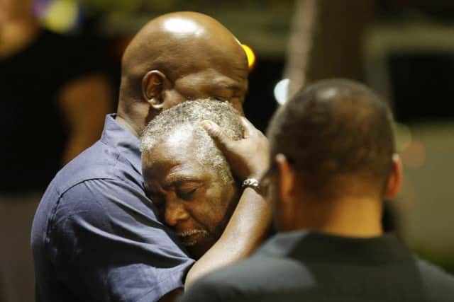 Worshippers comfort each other following a group prayer across the street from the scene of the shooting. Picture: AP