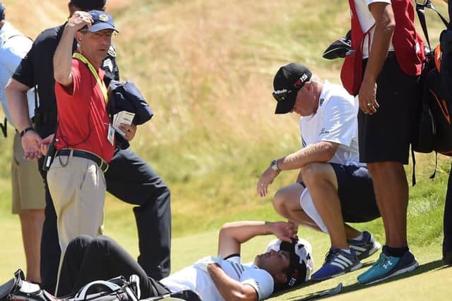 Jason Day of Australia is tended to by caddie Colin Swatton as he lays on the ninth green after falling due to dizziness. Picture: Getty Images
