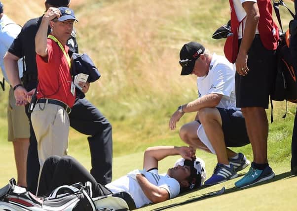 Jason Day of Australia is tended to by caddie Colin Swatton as he lays on the ninth green after falling due to dizziness. Picture: Getty Images