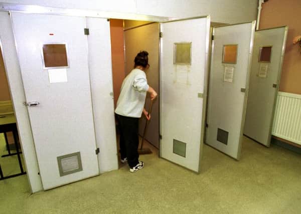 A prisoner mops one of the holding cells in reception at Cornton Vale Prison.