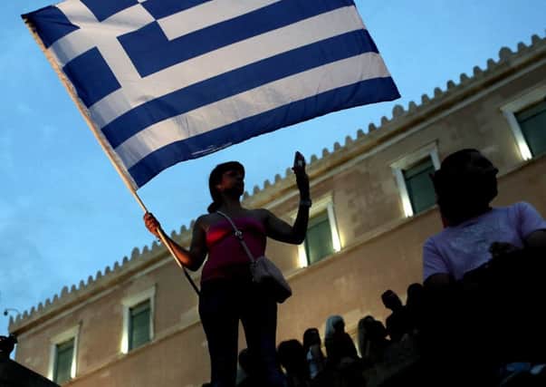 An anti-austerity protester holds a Greek flag in front of the parliament in Athens. Picture: AFP/Getty