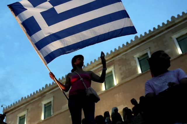 An anti-austerity protester holds a Greek flag in front of the parliament in Athens. Picture: AFP/Getty