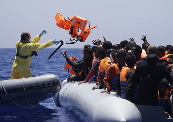 A Belgian sailor from the Godetia rescues migrants off Libya on Tuesday, one of the EU naval ships taking part in operation Triton. Picture: AP