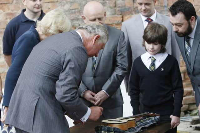 The Duke Rothesay signs a ukulele for Scott Hutchison, second right, during a visit to the refurbished Clutha bar. Picture: Getty Images
