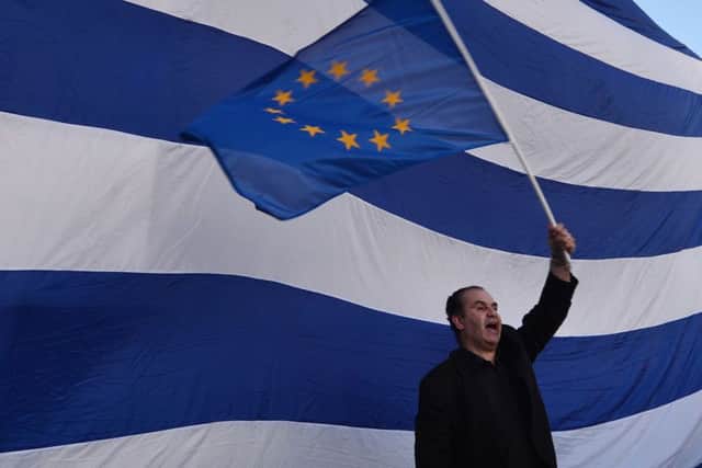 A man waves an European flag in front of giant Greek one in front of the Greek parliament in Athens. Picture: AFP/Getty Images