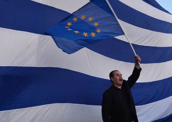 A man waves an European flag in front of giant Greek one in front of the Greek parliament in Athens. Picture: AFP/Getty Images