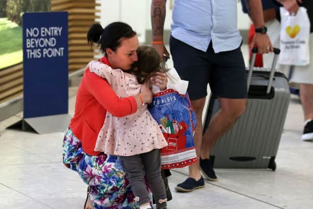 Helen and Darren Tait are greeted by their daughter as they arrive back at Glasgow from Tunisia. Picture: PA