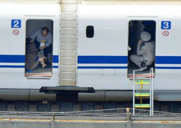A security official and two passengers can be seen reacting to the incident on board the train. Picture: AP/Kyodo News