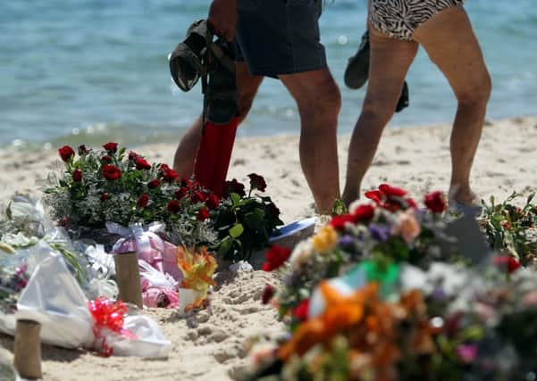 Tourists look at flowers that have been laid on the beach near the RIU Imperial Marhaba hotel in Sousse, Tunisia. Picture: PA