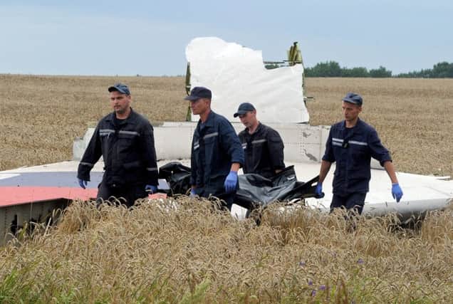 Ukrainian rescue workers walk past a piece of wreckage of Malaysian Airlines Flight MH17 after it was shot down last July. Picture: Getty
