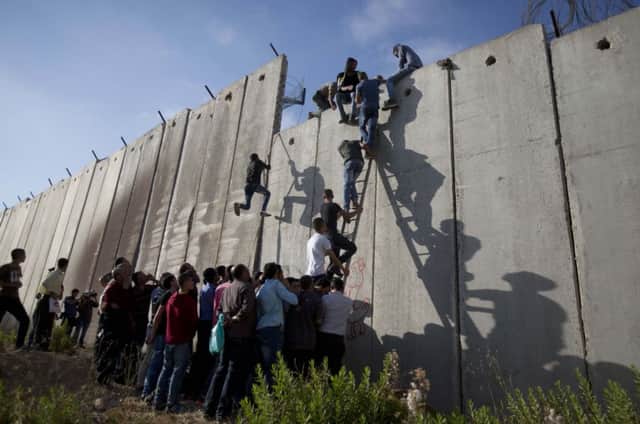 Palestinians use a ladder to climb over the separation barrier with Israel on their way to pray at the alAqsa Mosque in Jerusalem. Picture: AP