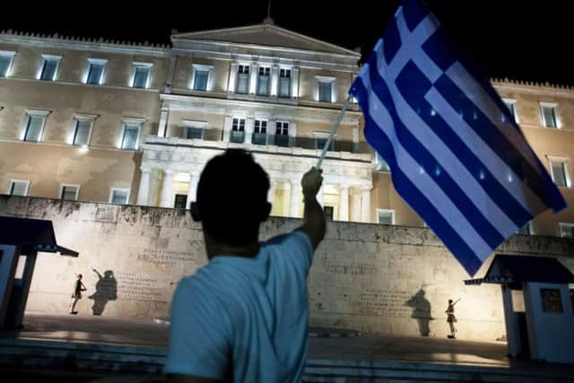 A man holds a Greek national flag as he celebrates the No vote in a crucial bailout referendum. Picture: AFP/Getty Images