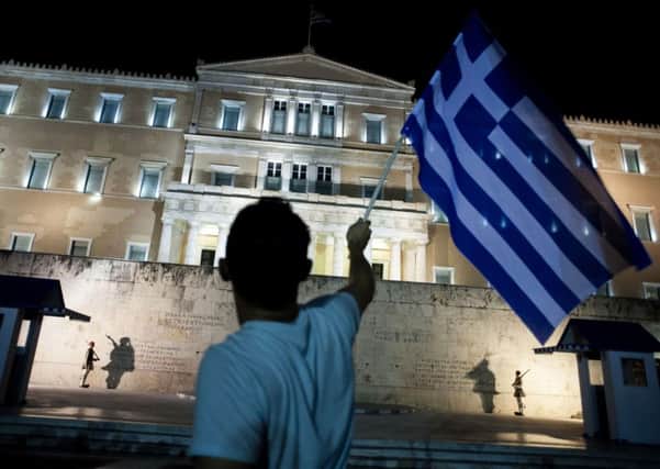 A man holds a Greek national flag as he celebrates the No vote in a crucial bailout referendum. Picture: AFP/Getty Images