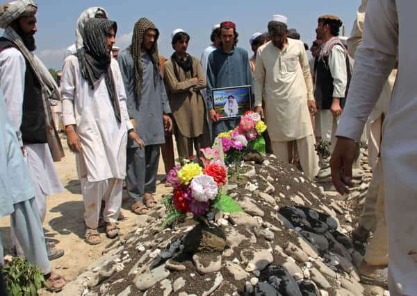 Mourners gather round the grave of an Afghan man killed by a suicide bomber at Camp Chapman. Picture: AFP