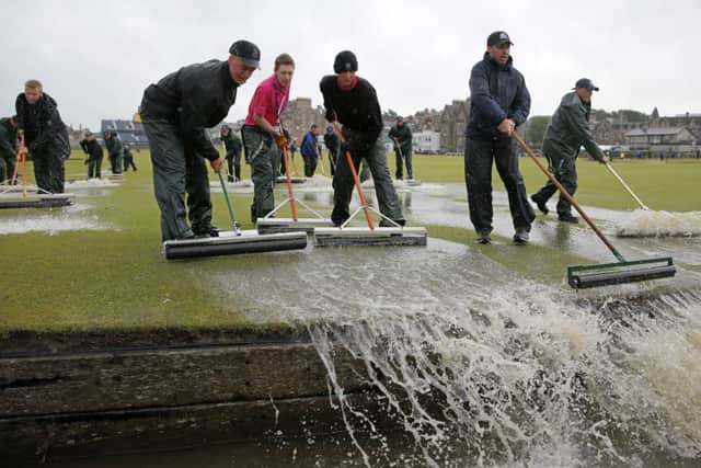 Groundsmen sweep water from the fairway at St Andrews. Picture: Getty