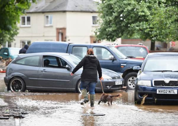 A woman walks her dog in Alyth, Scotland, passed the severe damage caused by yesterday's flooding. Picture: Getty