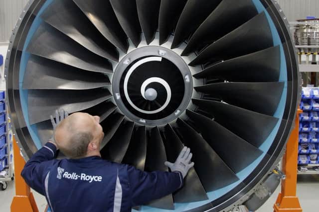 A worker scrubs the turbine of Rolls-Royce jet engine. Picture: Getty Images