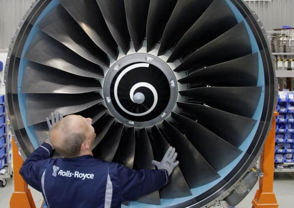 A worker scrubs the turbine of Rolls-Royce jet engine. Picture: Getty Images