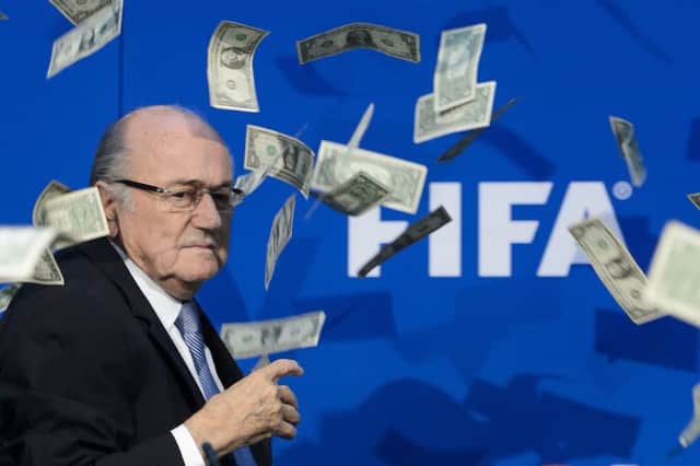 FIFA president Sepp Blatter looks on with fake dollars note flying around him. Picture: Getty