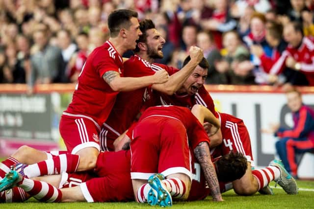 Team-mates mob Niall McGinn after scoring for Aberdeen. Picture: PA