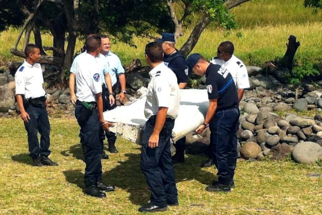 Police carry a piece of debris from an unidentified aircraft found in the coastal area of Saint-Andre de la Reunion. Picture: AFP