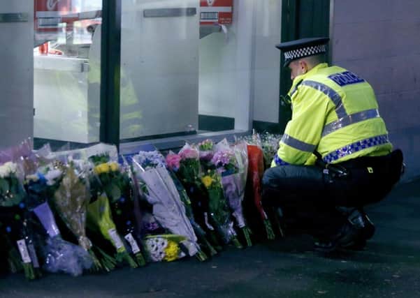 A policeman looks at flowers close to the scene in George Square, Glasgow, where a bin lorry crashed into a group of pedestrians and killed six last December. Picture: PA