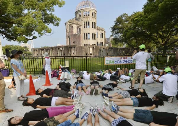 Youngsters stage a symbolic  die-in in front of the Atomic Bomb Dome in Hiroshima to mark the 70th anniversary of the dropping of the atomic bomb on the city. Picture: AP