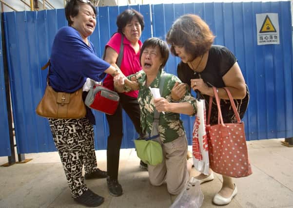 Bao Lanfang, whose daughter-in-law, son, and granddaughter were aboard Malaysia Airlines Flight MH 370, kneels in grief in Beijing. Picture: AP