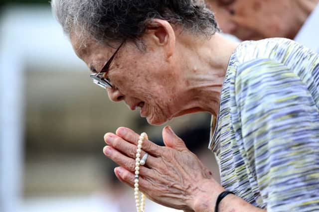 A woman cries as she offers prayers at the Peace Park in Nagasaki yesterday. Picture: AP