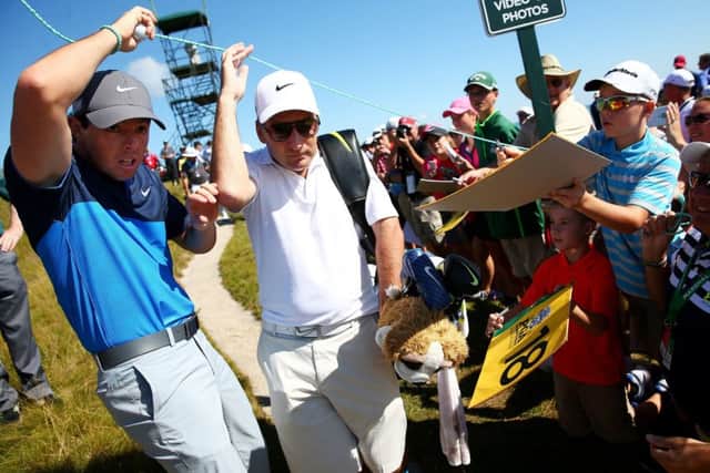 Rory McIlroy and his caddie JP Fitzgerald pass under a gallery rope during a practice round yesterday. Picture: Getty