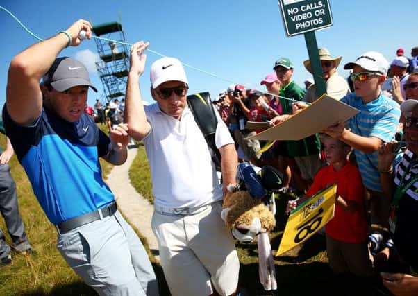 Rory McIlroy and his caddie JP Fitzgerald pass under a gallery rope during a practice round yesterday. Picture: Getty