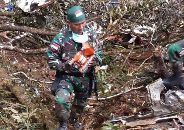 A soldier recovers the 'black box' flight data recorder from the aircraft crash site. Picture: AFP/Getty