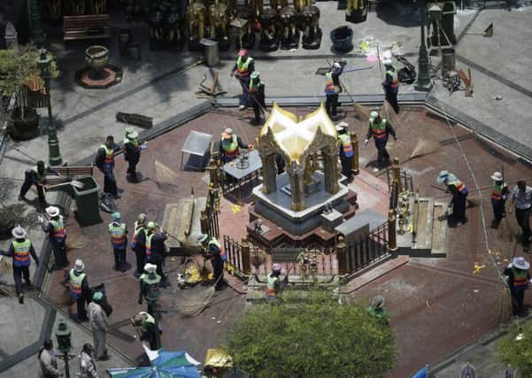Workers clean up the area around the statue of Phra Phrom, centre, at the Erawan Shrine the day after an explosion in Bangkok, Thailand. Picture: AP