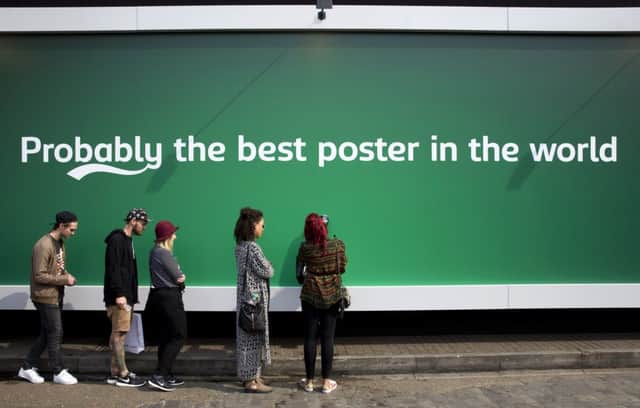 People queue by a billboard poster with a built in tap that is dispending free beer outside Carlsberg Truman Brewery in east London. Picture: Getty