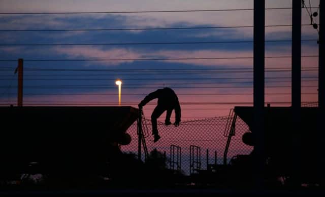 A migrant climbs over a fence on to the tracks near the Eurotunnel site at Coquelles in Calais. Picture: PA