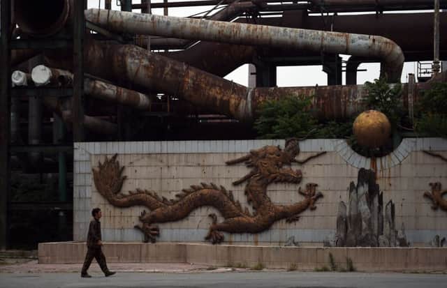 A worker walks past a sculpture of a dragon at an iron and steel plant in Beijing. The facility closed after being identified as the Chinese capital's biggest polluter. Picture: AFP/Getty