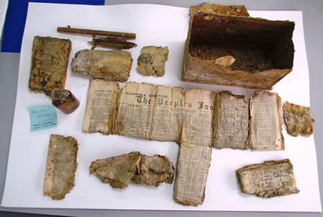 The contents of a 121-year-old time capsule. A metal tin, about the size of a shoe box, contained a folded newspaper, a paper scroll and a bottle of what appears to be whisky. Picture: PA