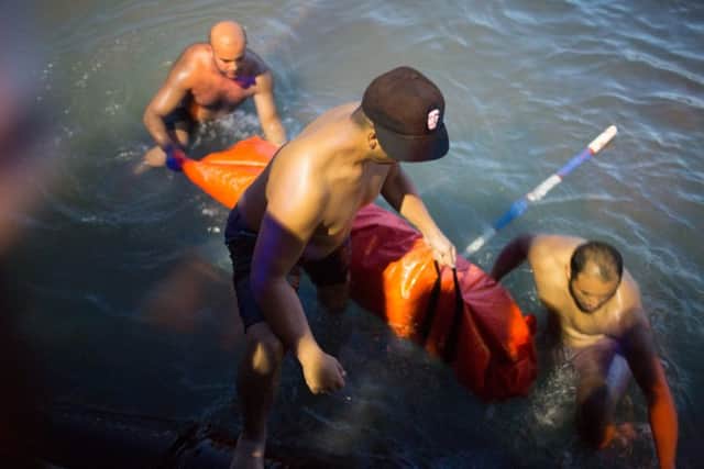 Rescuers remove the body of a migrant after their boat sank off the coast of in Zuwara, Libya. Picture: AP